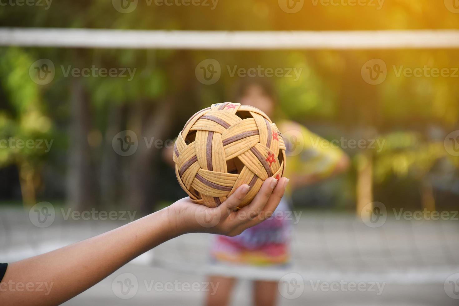 sepak takraw bal, zuidoosten Aziatisch landen traditioneel sport, Holding in hand- van jong Aziatisch vrouw sepak takraw speler in voorkant van de netto voordat het werpen het naar een ander speler naar trap over- de netto. foto