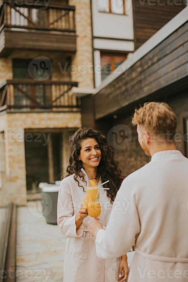 jong paar ontspannende Aan de buitenshuis terras en drinken vers oranje sap foto