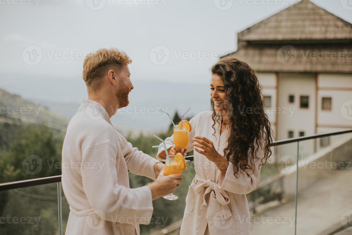 jong paar ontspannende Aan de buitenshuis terras en drinken vers oranje sap foto