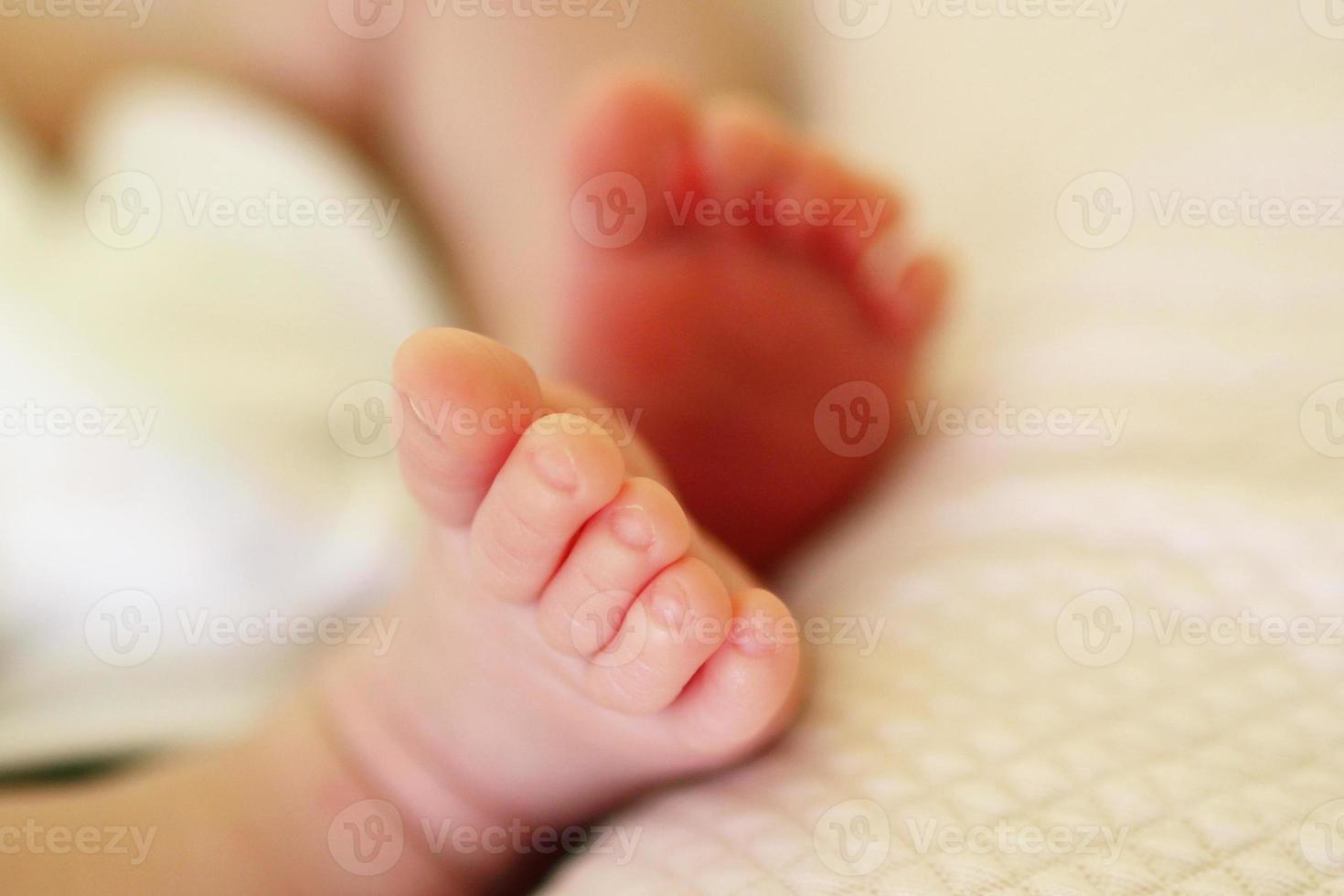 klein delicaat voeten van pasgeboren baby Aan een wit bed. foto
