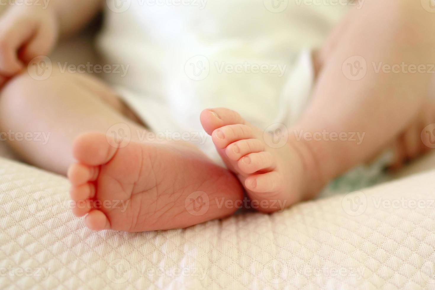 klein delicaat voeten van pasgeboren baby Aan een bed. foto