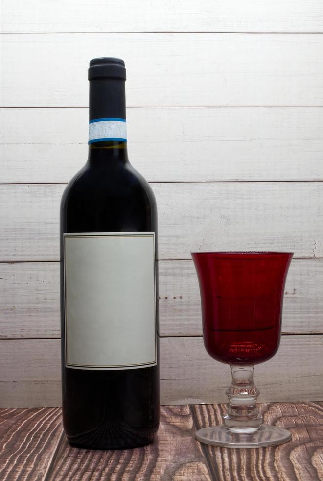 fles van rood wijn met blanco etiket en rood glas foto