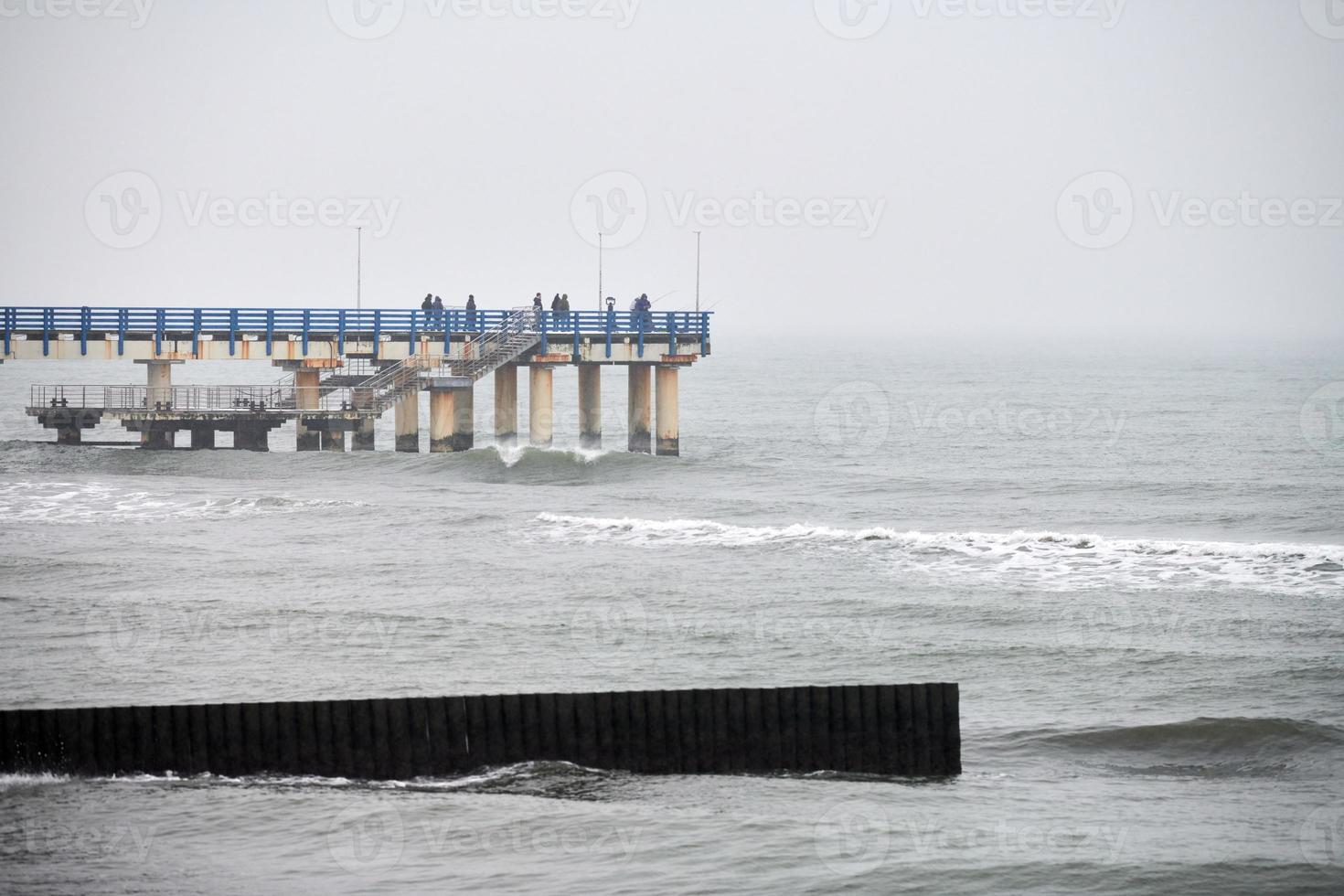 oude lange houten golfbrekers in zeegolven, winterlandschap foto