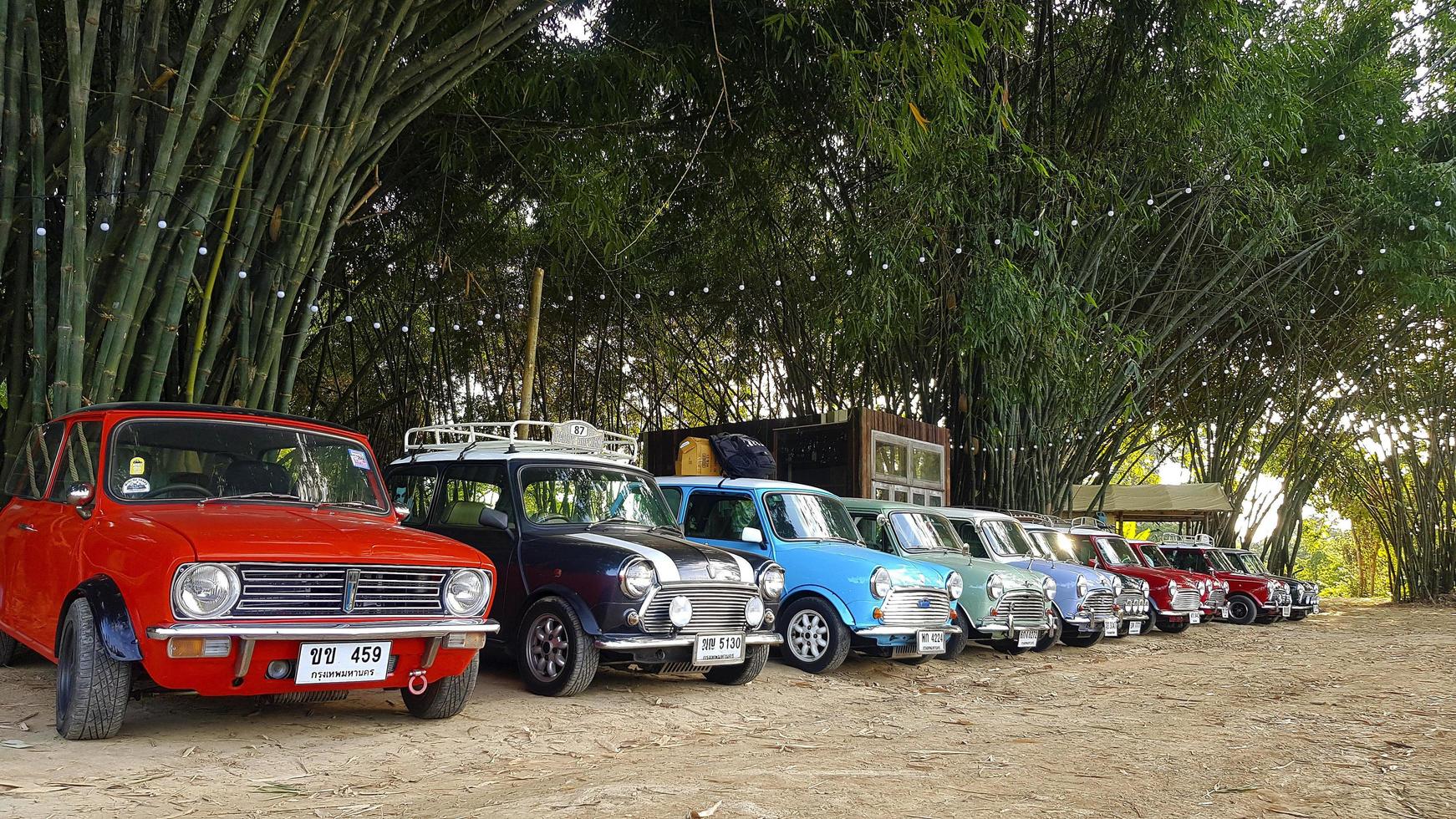 Nakhon nee, Thailand -december 5, 2020 veel Austin mini kuiper of klassiek auto geparkeerd Aan straat met bamboe Woud en huis of huis achtergrond met kopiëren ruimte. groep van wijnoogst of retro voertuig. foto