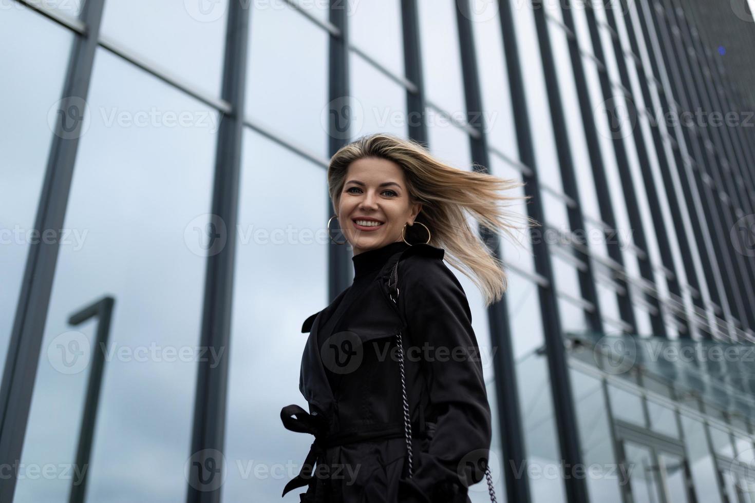 vrouw zakenvrouw met vliegend haar- in de wind tegen de backdrop van een kantoor gebouw foto