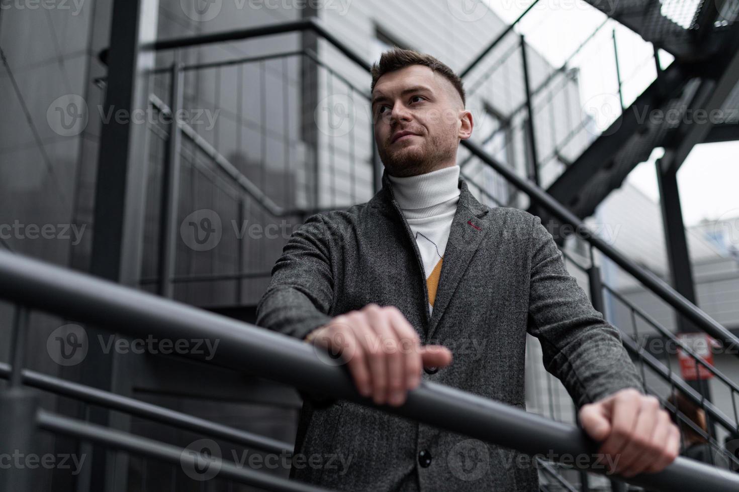 brutaal portret van een middelbare leeftijd Mens Aan een grijs metaal trappenhuis in de buurt een modern gebouw foto