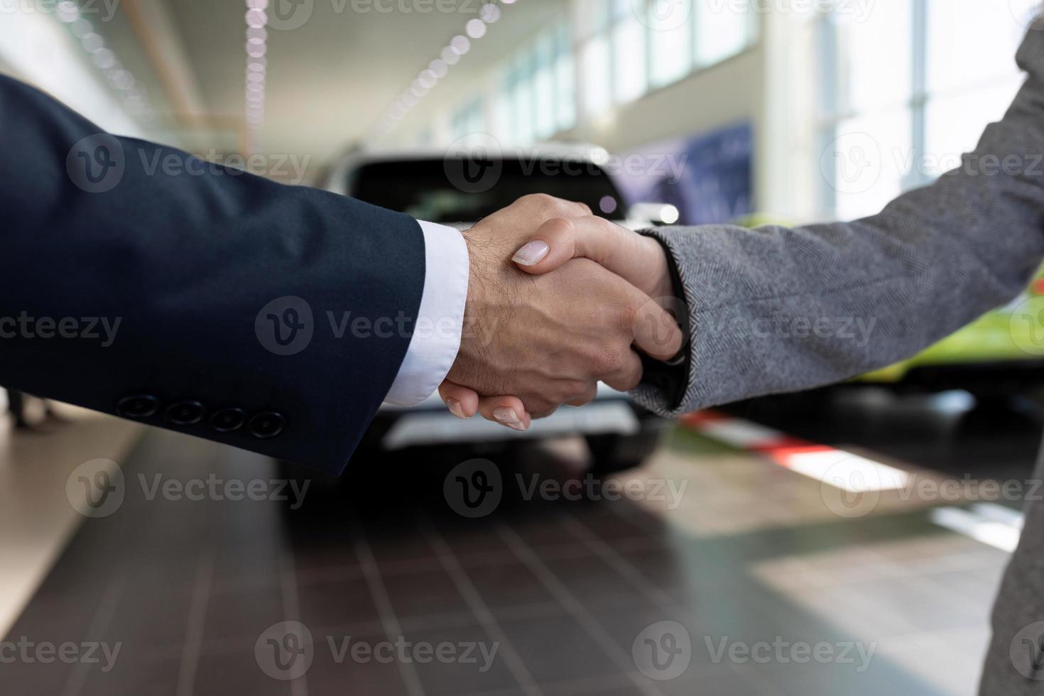 handdruk tegen de backdrop van een auto handel Bij een overeenkomst, de concept van buying een auto Aan huren foto