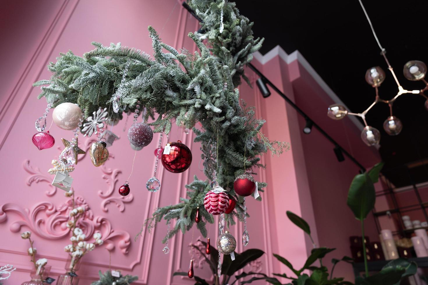 samenstelling van natuurlijk pijnboom naalden hangende van de plafond met Kerstmis decoraties in de interieur van een bloemist winkel foto