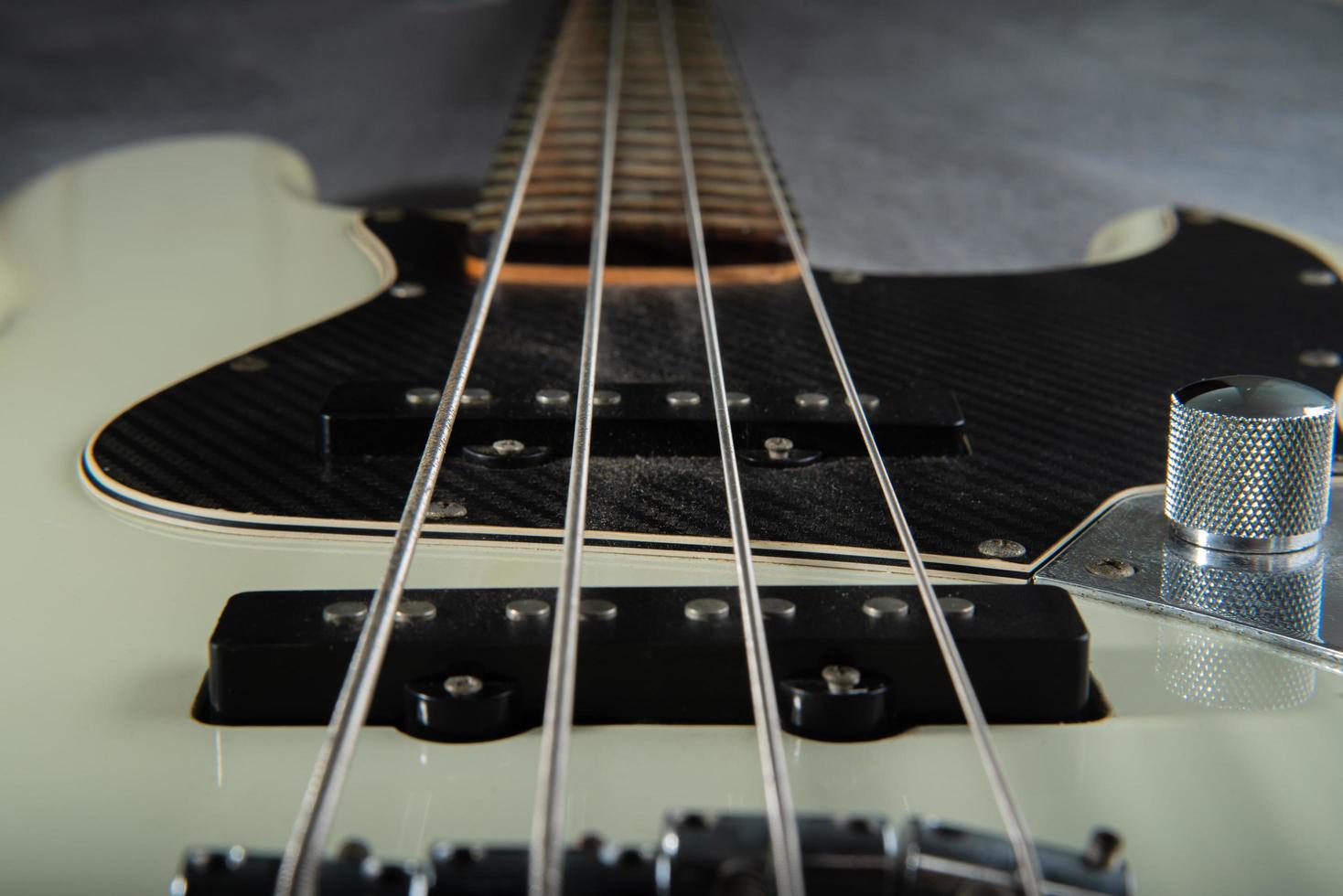 dichtbij omhoog gitaar bas draad details , vier ijzer snaren, wit en zwart kleur foto