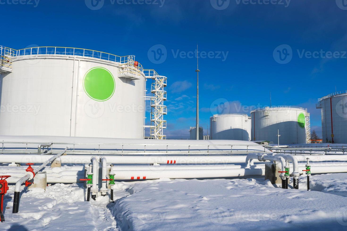 groot wit ijzer metaal industrieel tanks voor opslagruimte van brandstof, benzine en diesel en pijpleiding met kleppen en flenzen Bij de raffinaderij in de winter foto