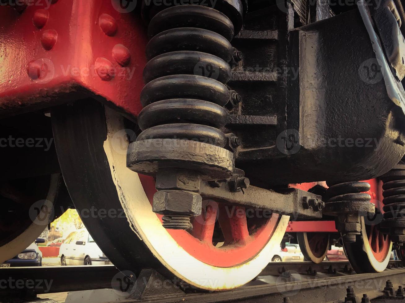 groot ijzer wielen van een rood en zwart trein staand Aan rails en suspensie elementen met veren van een oud industrieel stoom- locomotief foto