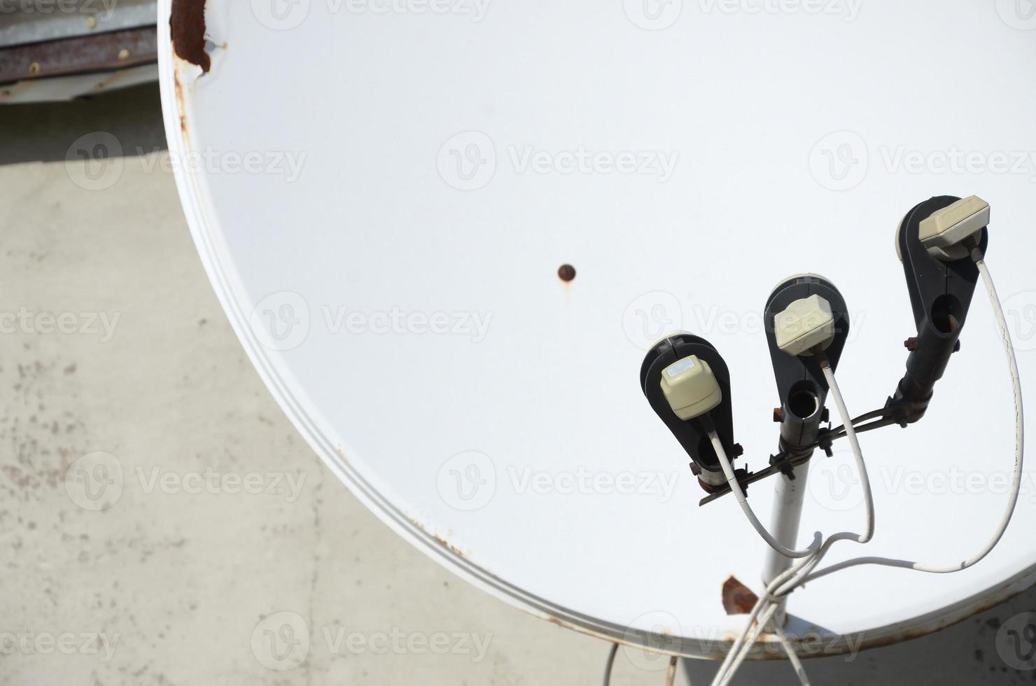 wit satelliet schotel met drie converters gemonteerd Aan woonachtig gebouw op het dak beton muur. satelliet televisie foto