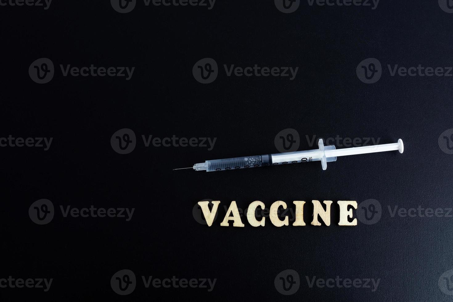 een injectiespuit met een dosis van geneeskunde of vaccin Aan een zwart achtergrond met een ruimte voor de tekst vaccinaties tegen de influenza coronavirus foto