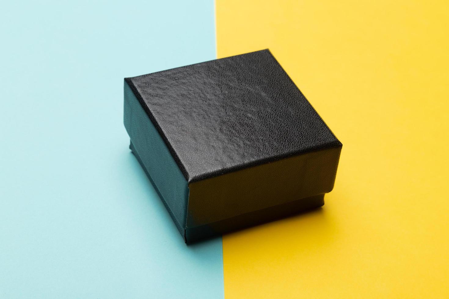 mini zwarte doos geïsoleerd op half gele half blauwe achtergrond foto