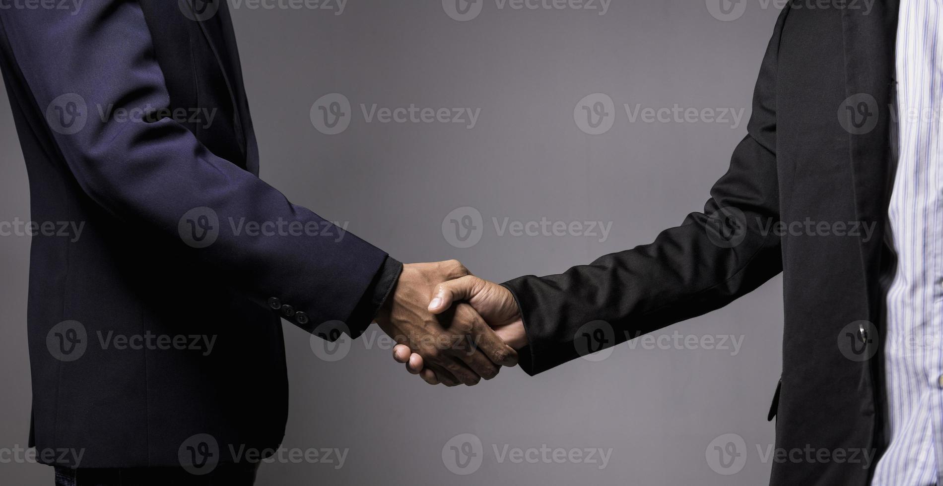 twee zelfverzekerd zakenman schudde handen gedurende kantoor vergaderingen. foto