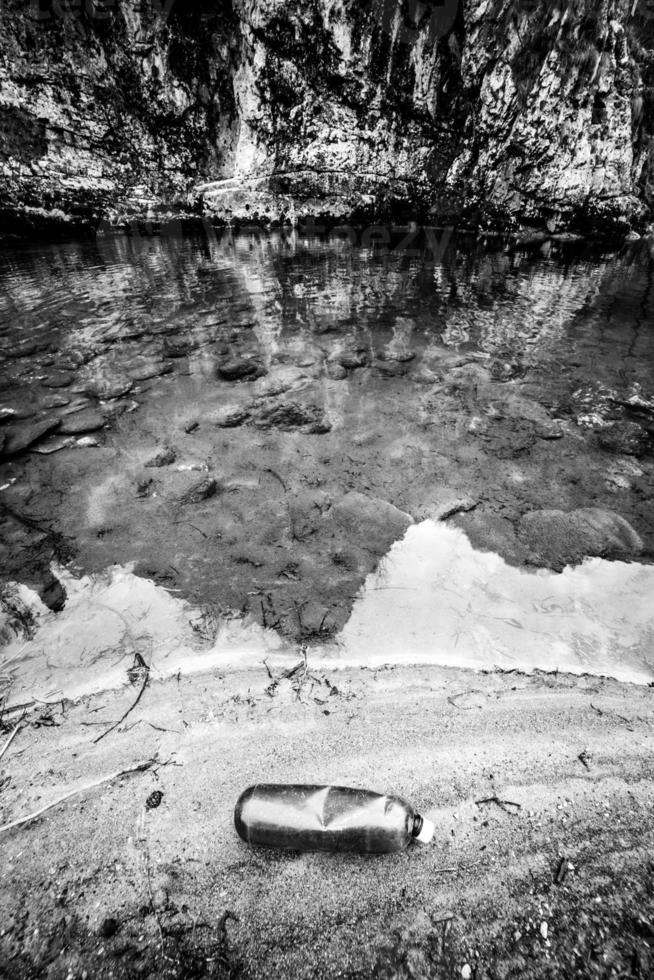 plastic fles verlaten Aan de bank van een rivier- concept van verontreiniging en milieu duurzaamheid foto