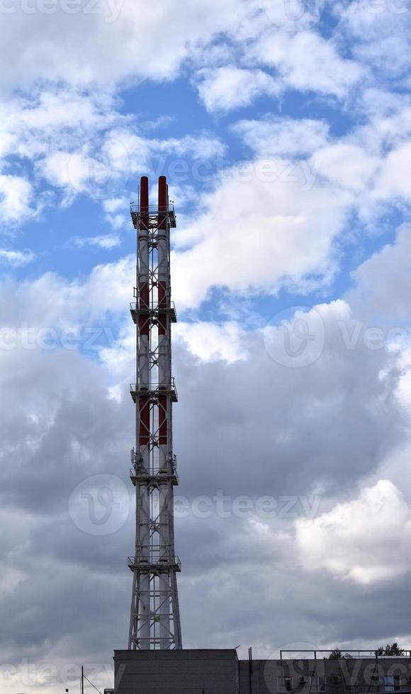 staal pijp van een thermisch macht fabriek tegen de achtergrond van blauw lucht en wolken in de buurt de huis. foto