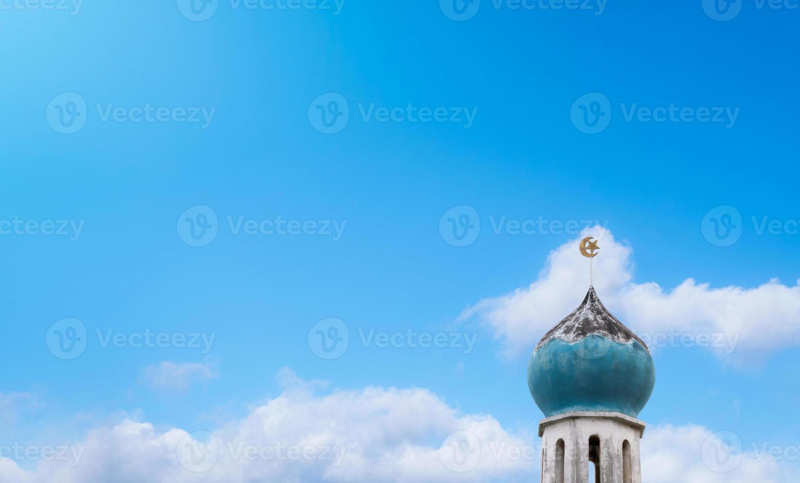 halve maan maan en ster Bij een top van oud moskee over- de wolken Aan blauw lucht achtergrond. de moskee is een belangrijk voor Islamitisch religie, eid al-adha, eidi mubarak, eid al fitr, ramadan kareem foto