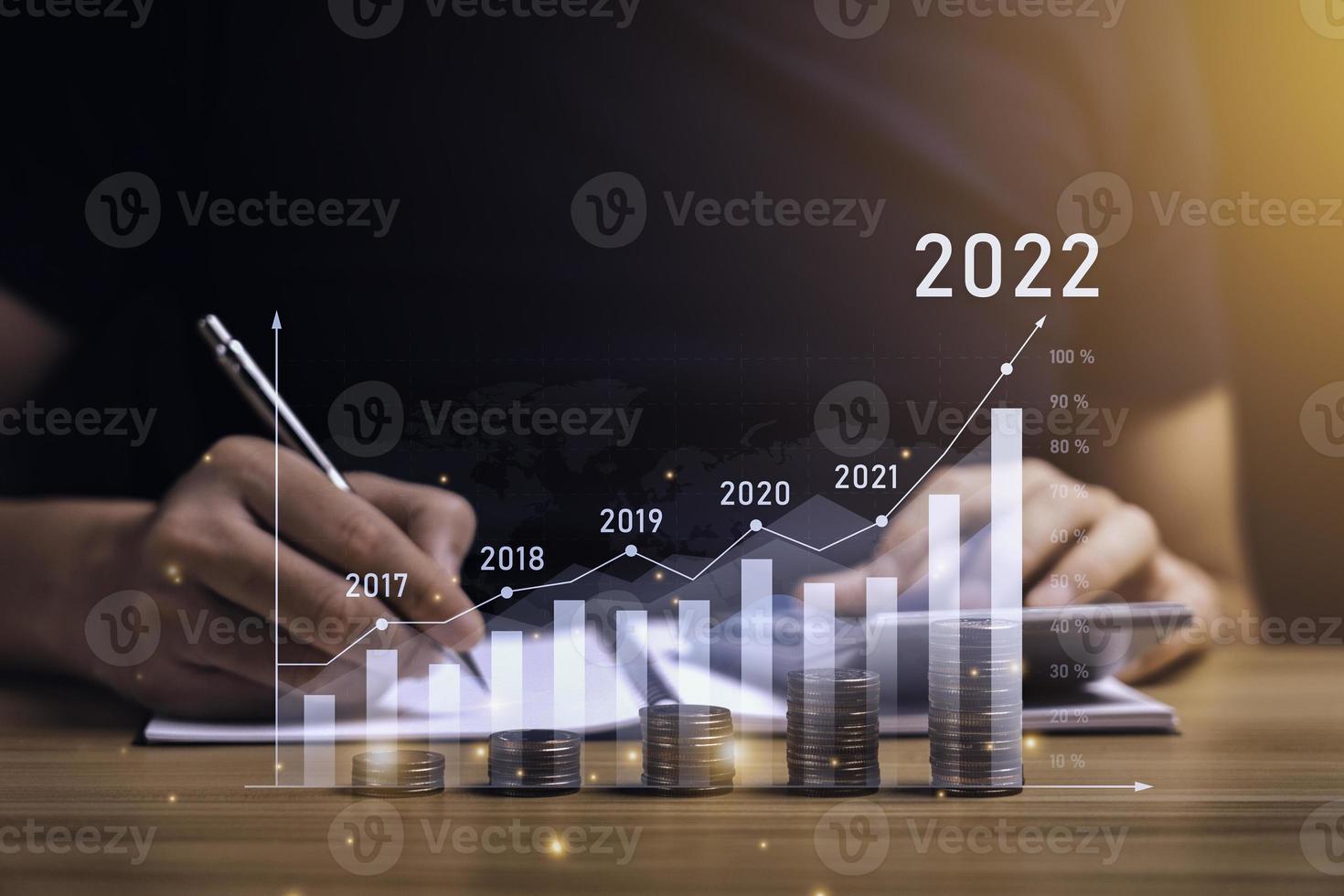 zakenman planning 2022 bedrijf groei Aan bureau met virtueel hologram tabel grafiek. berekenen inkomen en winst Aan investeringen en een toenemen in de indicatoren van positief groei foto