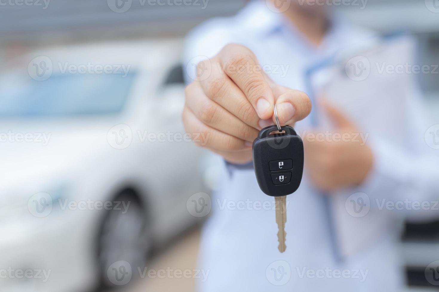 verkoper is draag- de auto sleutels geleverd naar de klant Bij de toonzaal met een laag interesseren bieden. speciaal Promotie foto