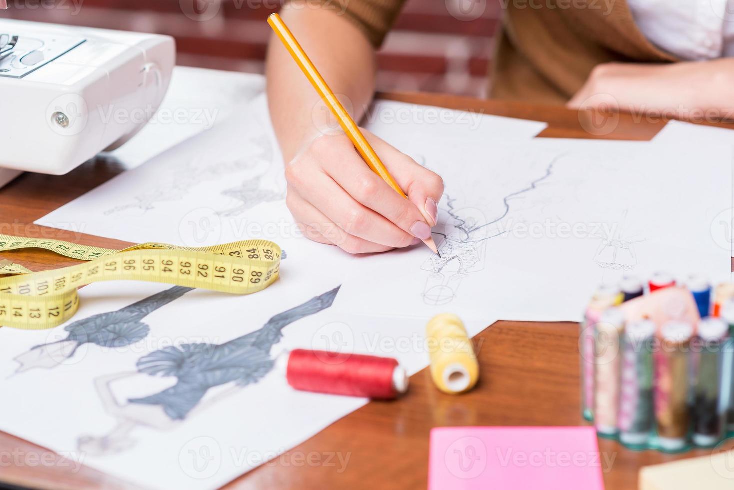 creëren nieuw mode Look. detailopname van vrouw tekening mode schetsen terwijl zittend Bij haar werken plaats foto