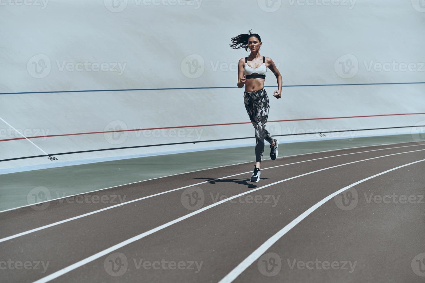 bereiken het beste resultaten. vol lengte van jong vrouw in sport- kleding jogging terwijl oefenen buitenshuis foto