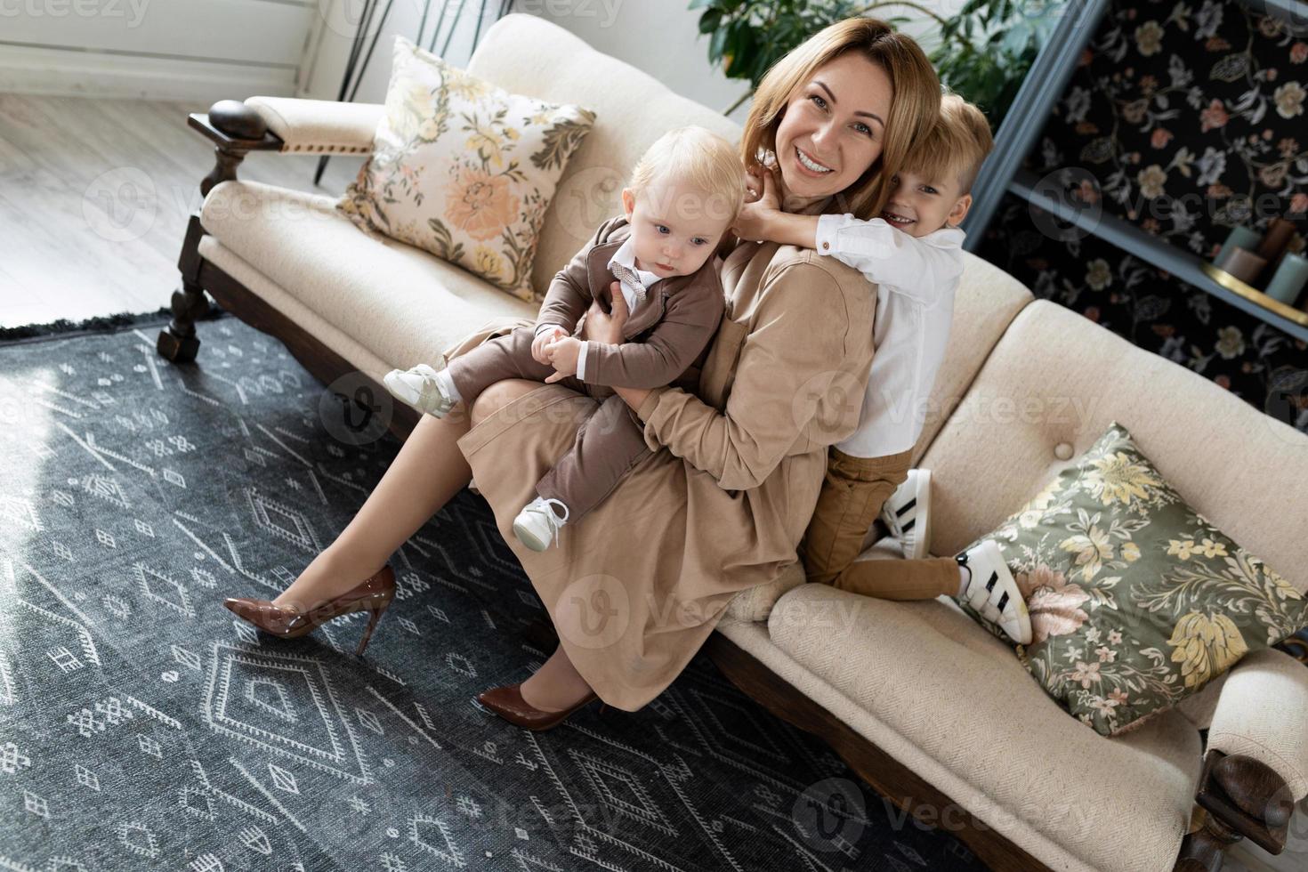 portret van een jong moeder met twee schattig zonen zittend Aan de sofa foto