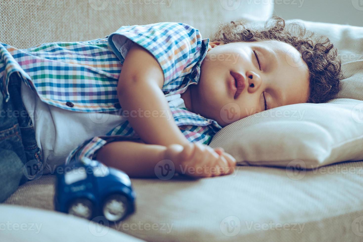 zoet dromen. weinig Afrikaanse baby jongen slapen terwijl aan het liegen Aan bankstel Bij huis foto