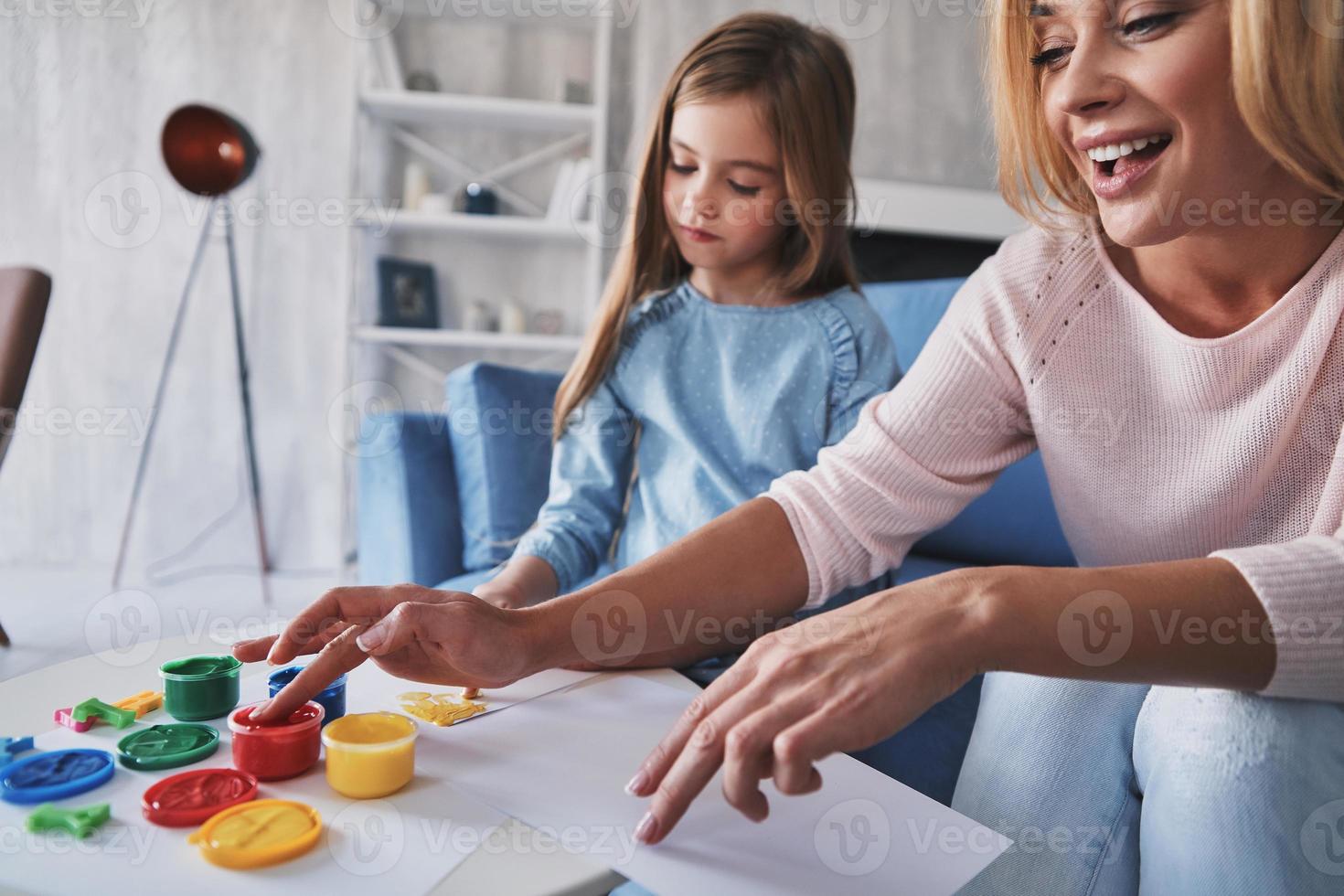 hun gemeenschappelijk hobby. moeder en dochter schilderij met vingers en glimlachen terwijl uitgeven tijd Bij huis foto