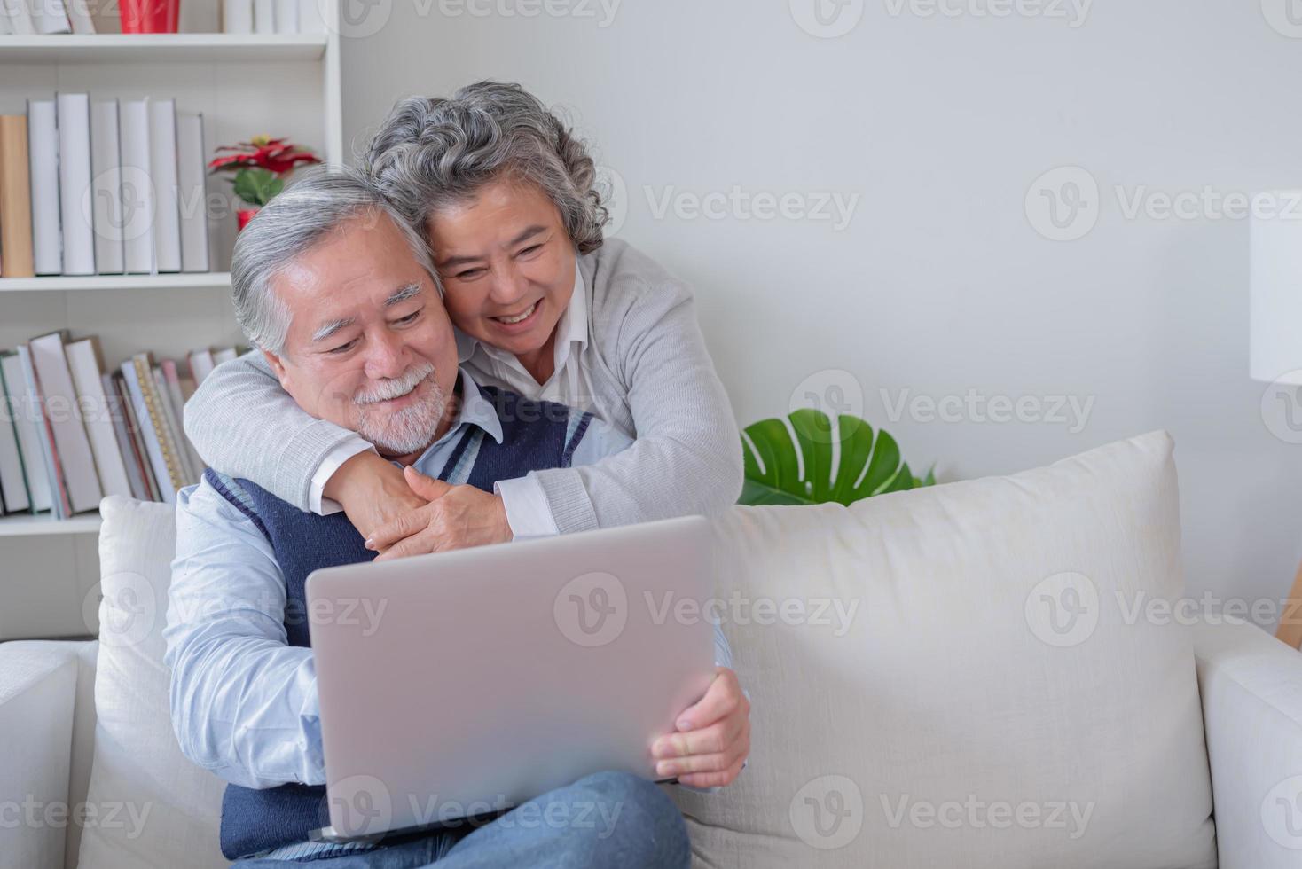 senior man en vrouw zitten Aan sofa kijken Bij computer notitieboekje zijn gelukkig foto