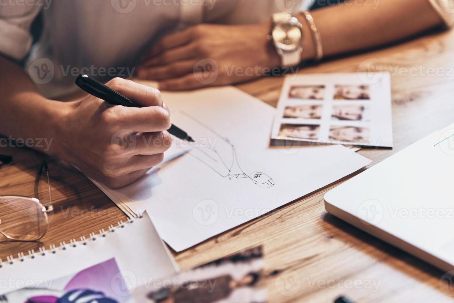 het beste ontwerpen. dichtbij omhoog top visie van jong vrouw werken Aan schetsen terwijl zittend in haar werkplaats foto