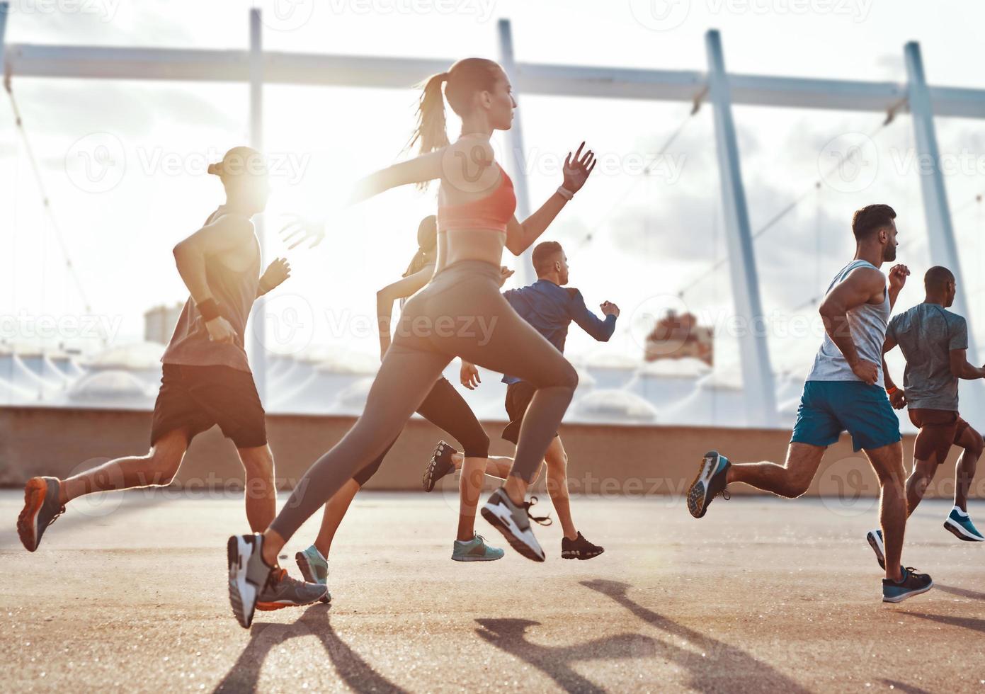 vol lengte van mensen in sport- kleding jogging terwijl oefenen Aan de trottoir buitenshuis foto