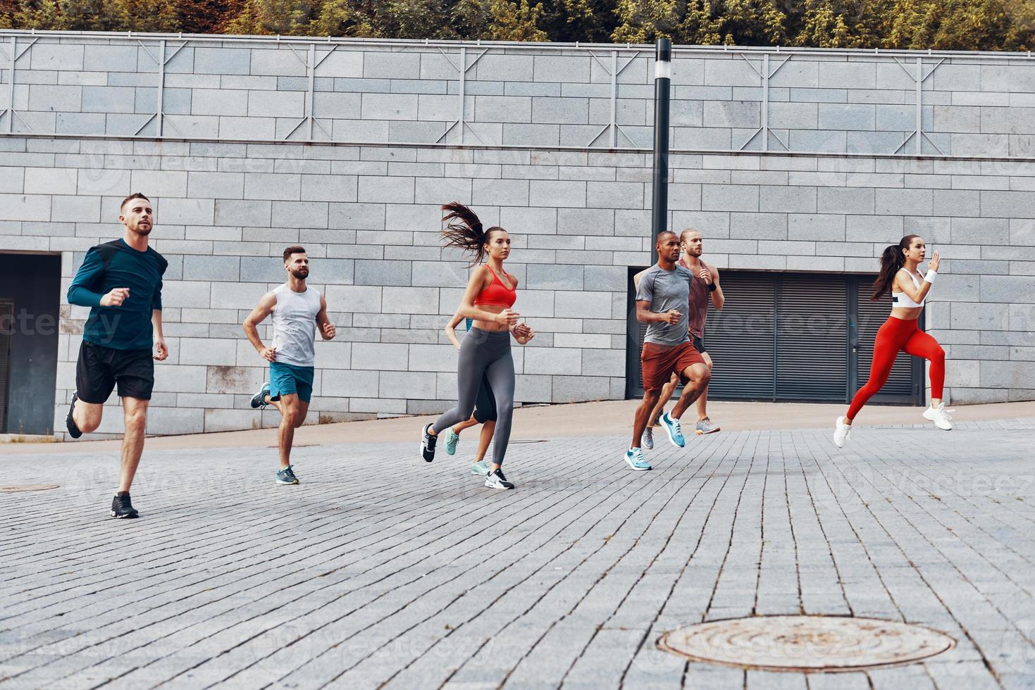 vol lengte van jong mensen in sport- kleding jogging terwijl oefenen buitenshuis foto