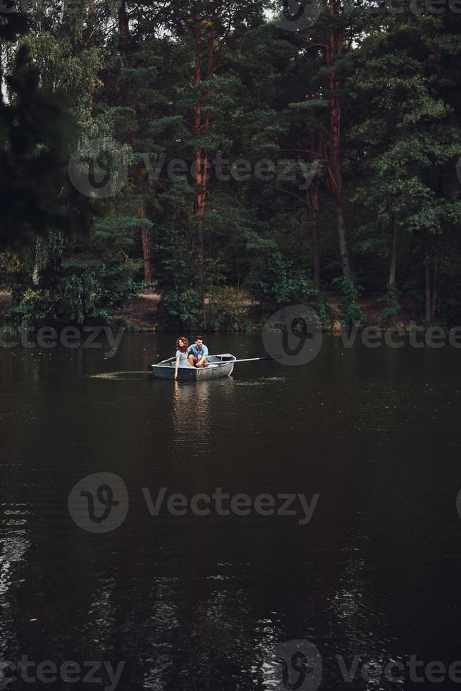 gemakkelijk vreugde van liefdevol. mooi jong paar genieten van romantisch datum terwijl roeien een boot foto