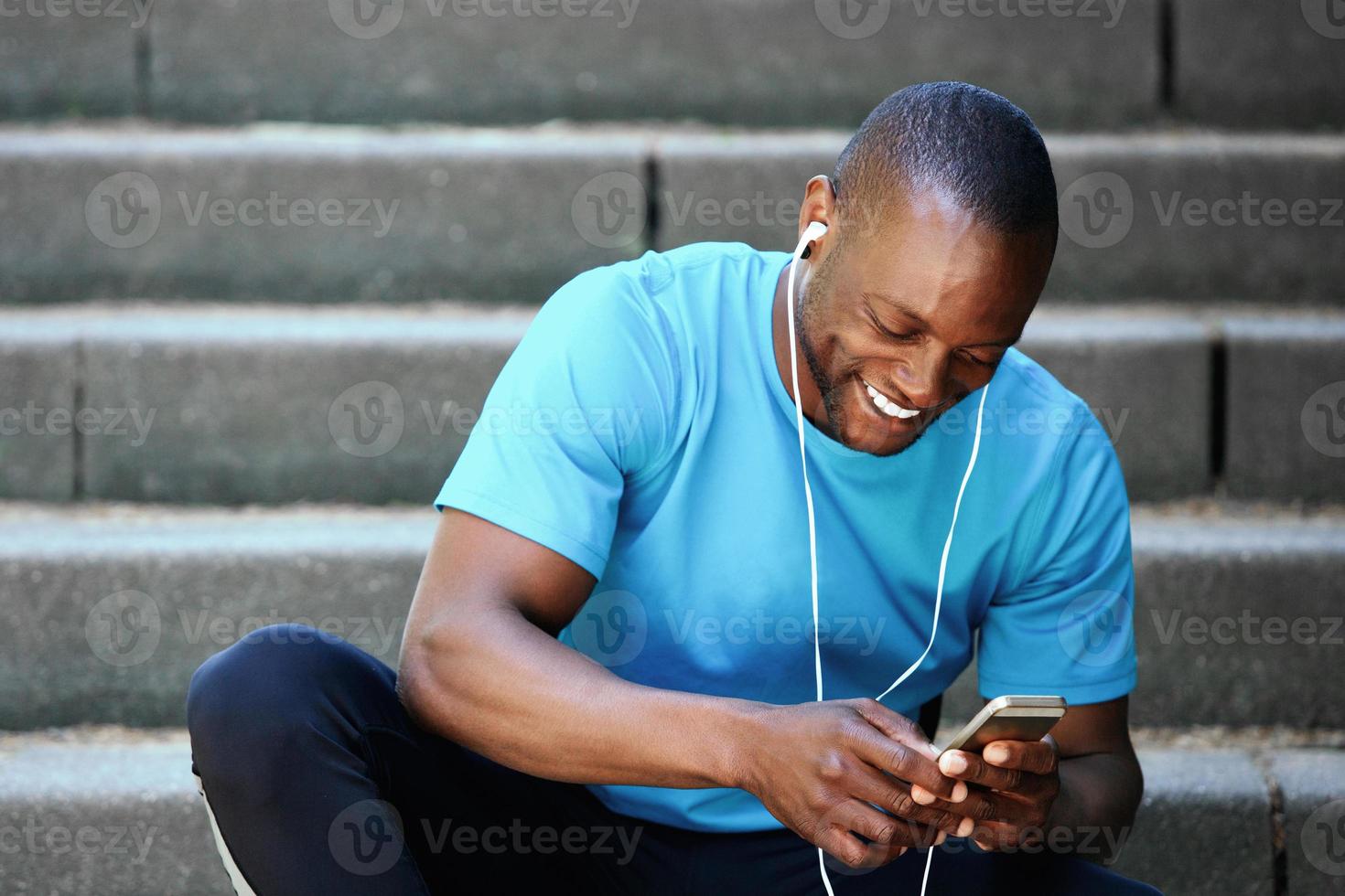 glimlachende man die naar mobiele telefoon kijkt en naar muziek luistert foto