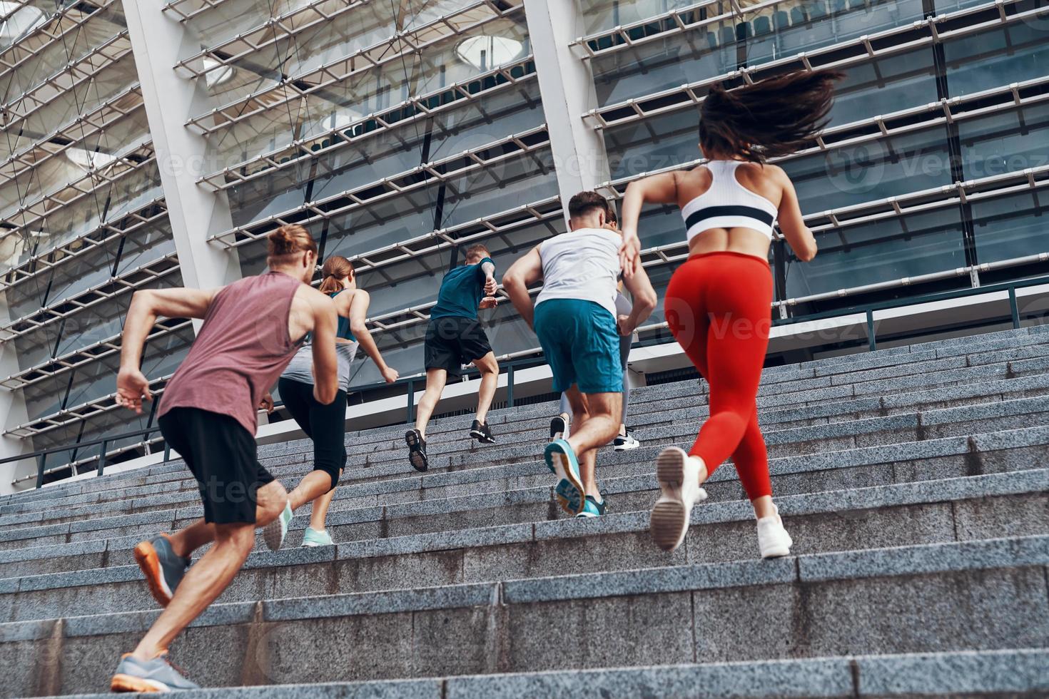 achterzijde visie van jong mensen in sport- kleding jogging terwijl oefenen Aan de trap buitenshuis foto