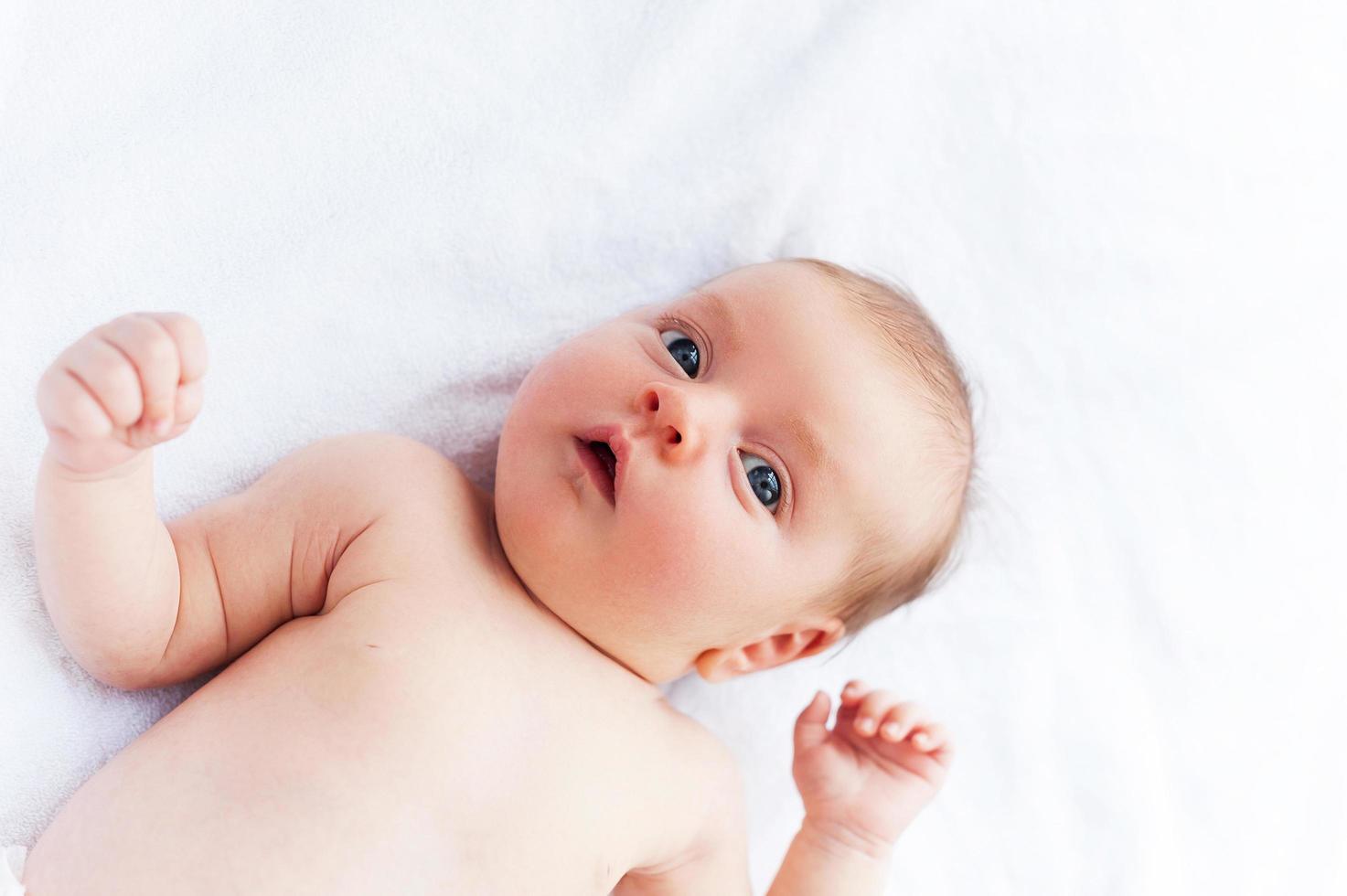 schattig en nieuwsgierig baby. top visie van schattig weinig baby aan het liegen in bed en op zoek Bij camera foto