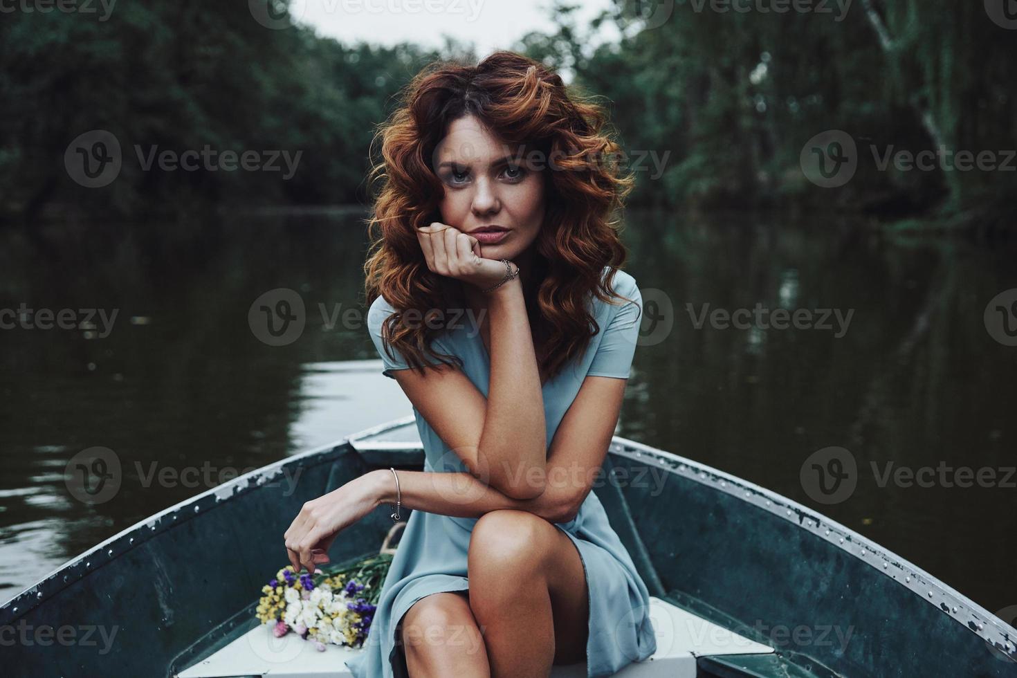 perfect vrouw. mooi jong vrouw in elegant jurk op zoek Bij camera terwijl zittend in de boot foto