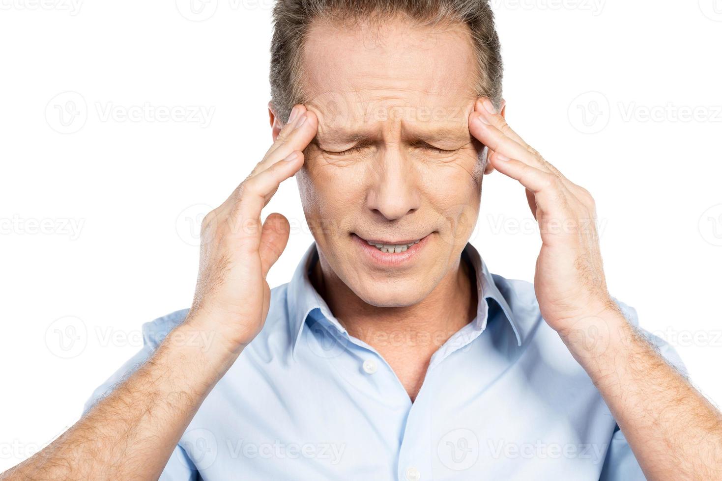 lijden van hoofdpijn. gefrustreerd volwassen Mens aanraken hoofd met vingers en houden ogen Gesloten terwijl staand tegen wit achtergrond foto