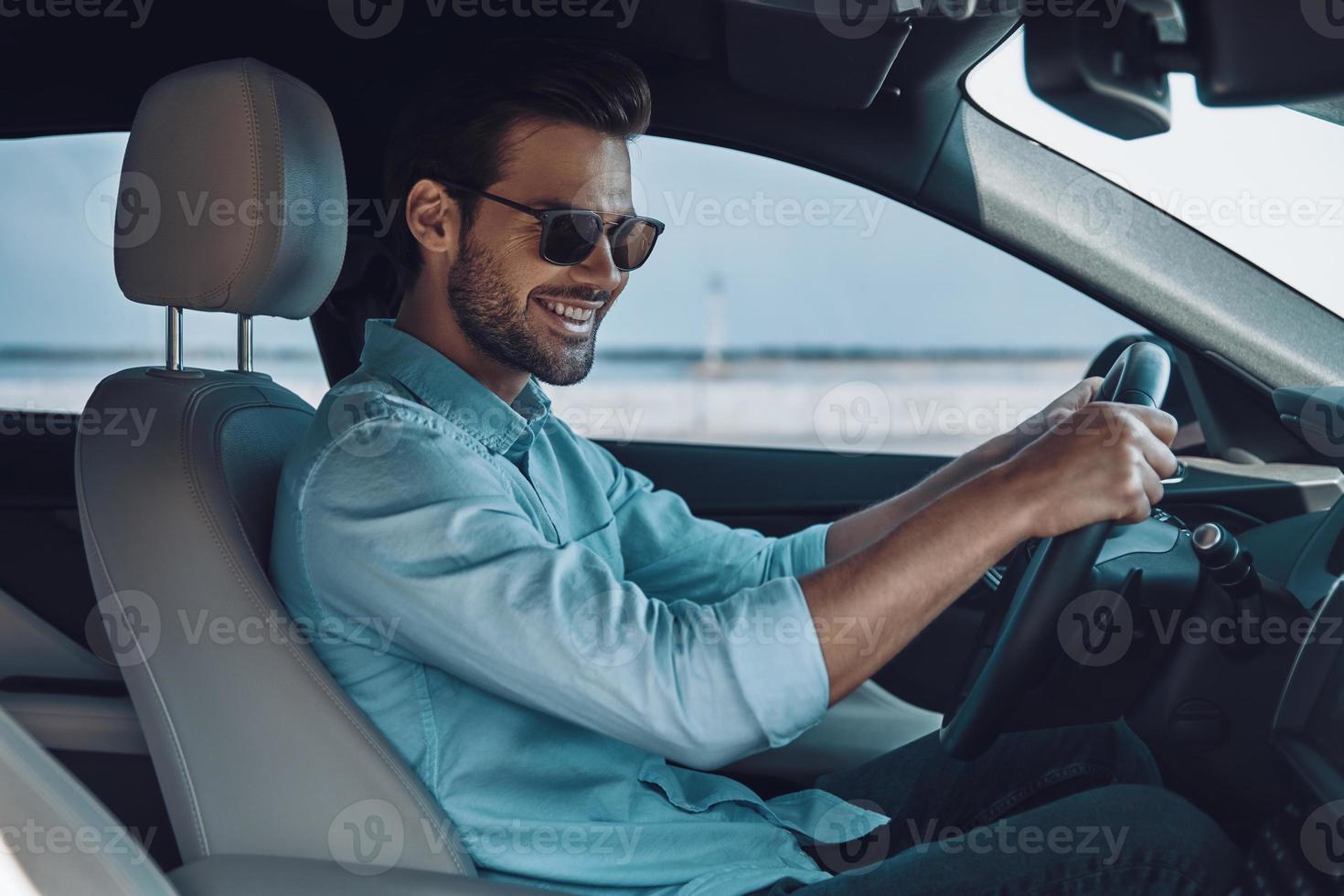 gelukkig naar rit nieuw auto. knap jong Mens in slim gewoontjes slijtage glimlachen terwijl het rijden een toestand auto foto