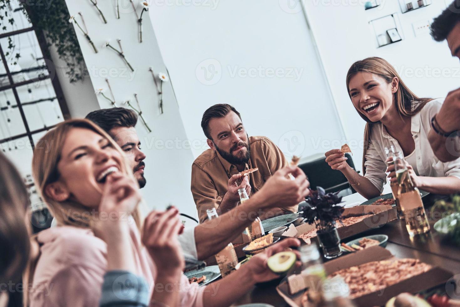 zo veel pret samen groep van jong mensen in gewoontjes slijtage aan het eten en glimlachen terwijl hebben een avondeten partij foto