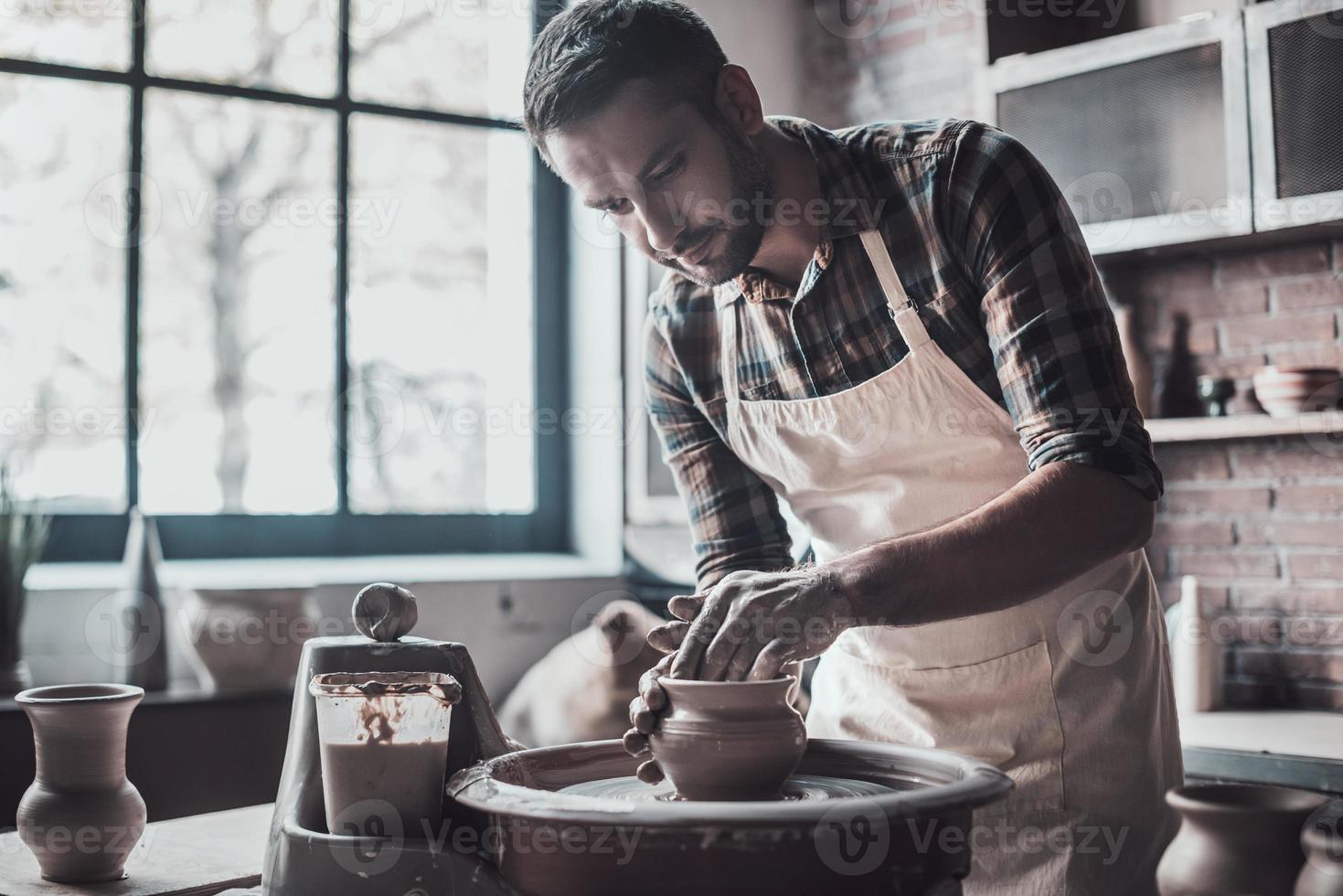 geconcentreerd Bij werk. zelfverzekerd jong Mens maken keramisch pot Aan de pottenbakkerij wiel foto