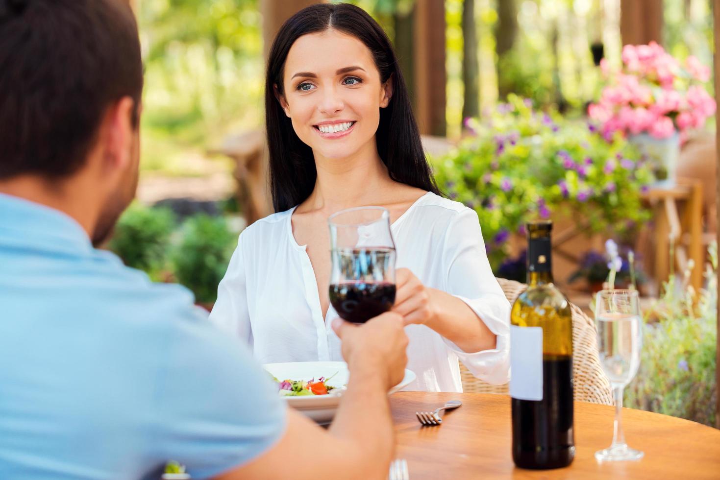 vieren hun liefde. mooi jong liefhebbend paar roosteren met rood wijn en glimlachen terwijl ontspannende in buitenshuis restaurant samen foto