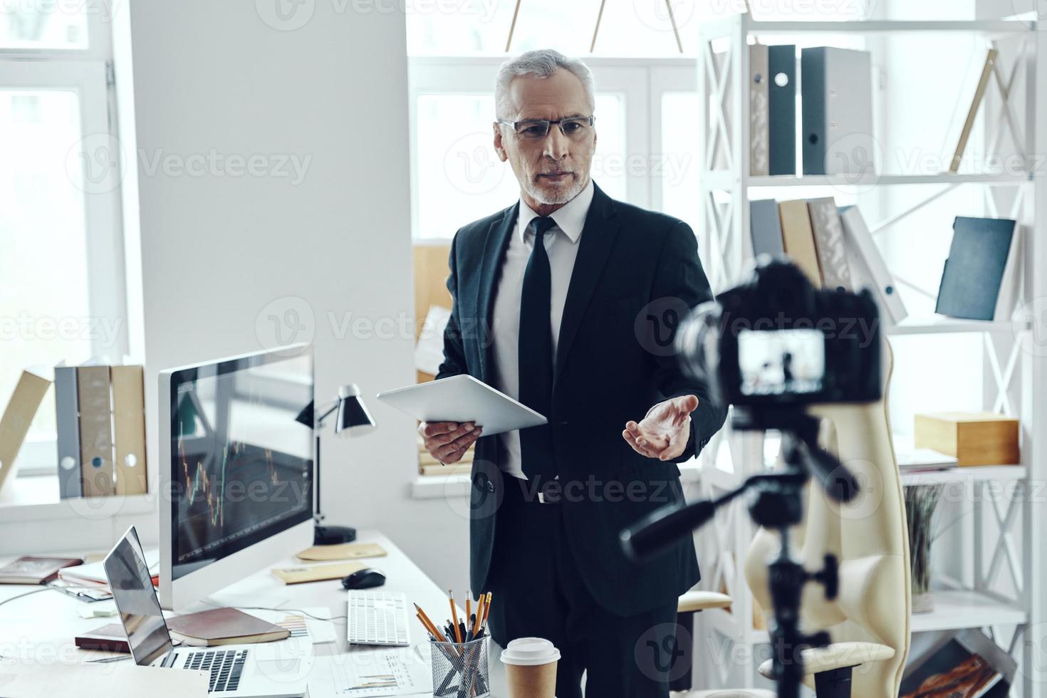 senior Mens in elegant bedrijf pak sharing zijn bedrijf ervaring terwijl maken sociaal media video foto