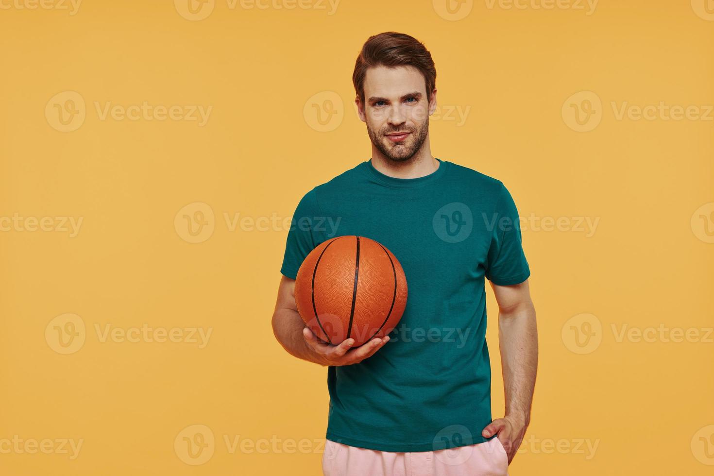 knap jong Mens Holding basketbal bal en op zoek Bij camera foto