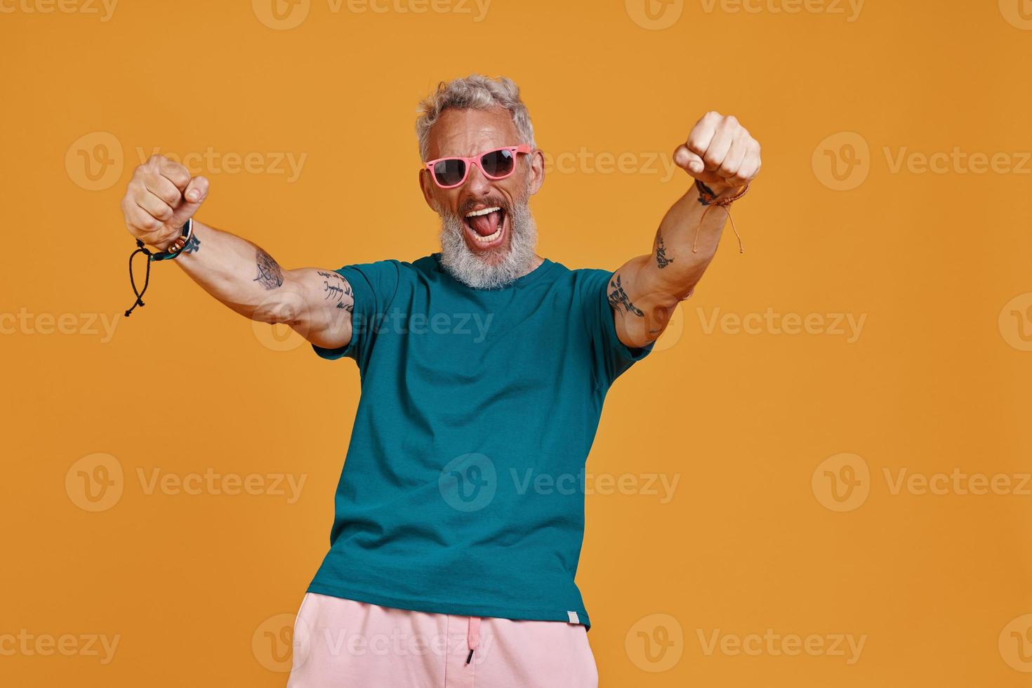 elegant senior Mens houden armen uitgestrekt en geschreeuw terwijl staand tegen oranje achtergrond foto