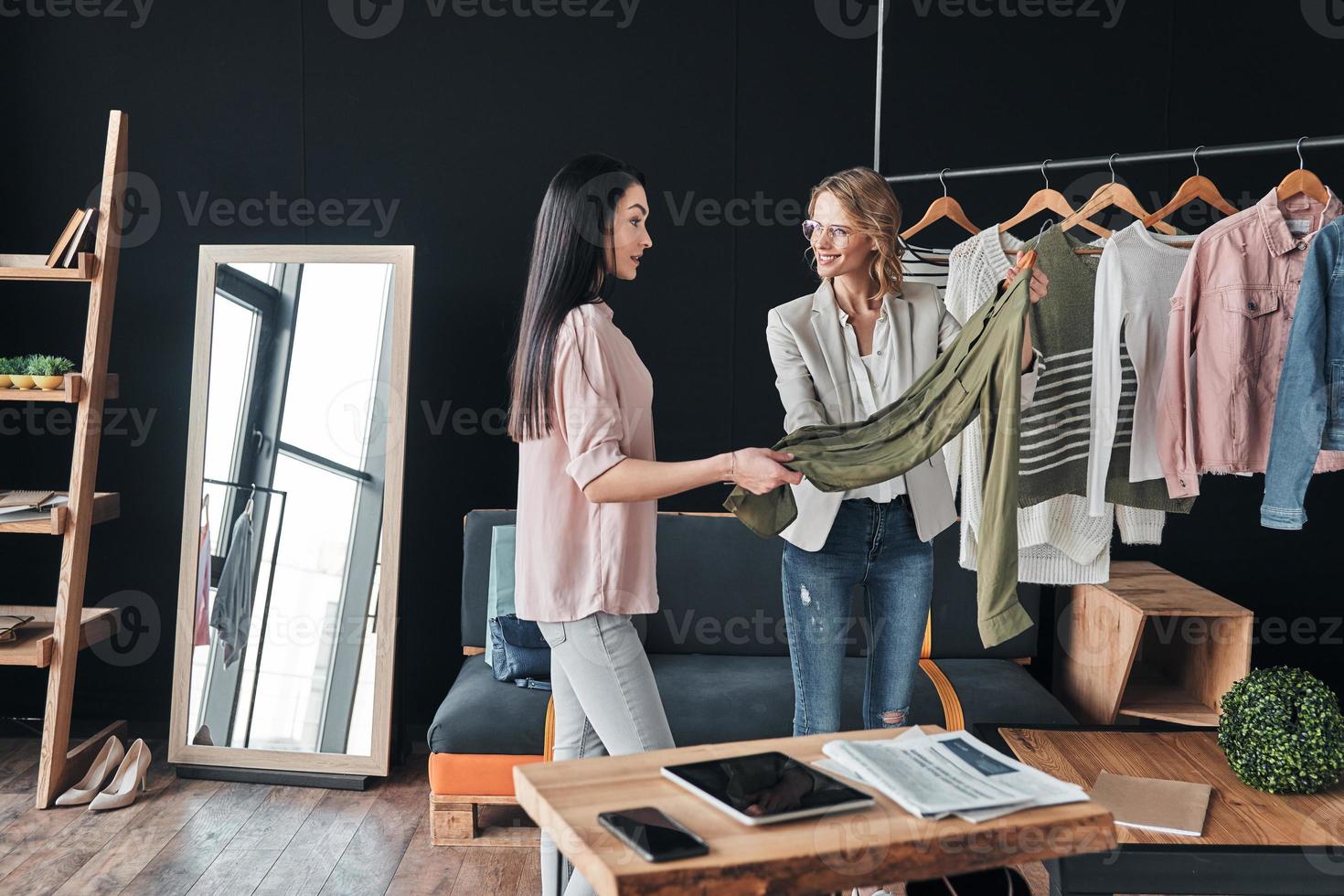 deze een is perfect voor jij. mooi jong vrouw helpen naar Kiezen kleren naar haar klant terwijl werken in de mode winkel foto