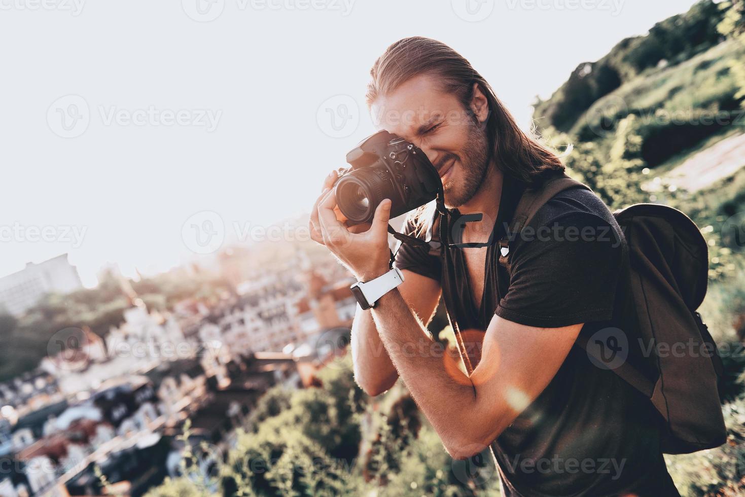 vastleggen elke moment. jong Mens in gewoontjes kleding fotograferen de visie terwijl staand Aan de heuvel buitenshuis foto