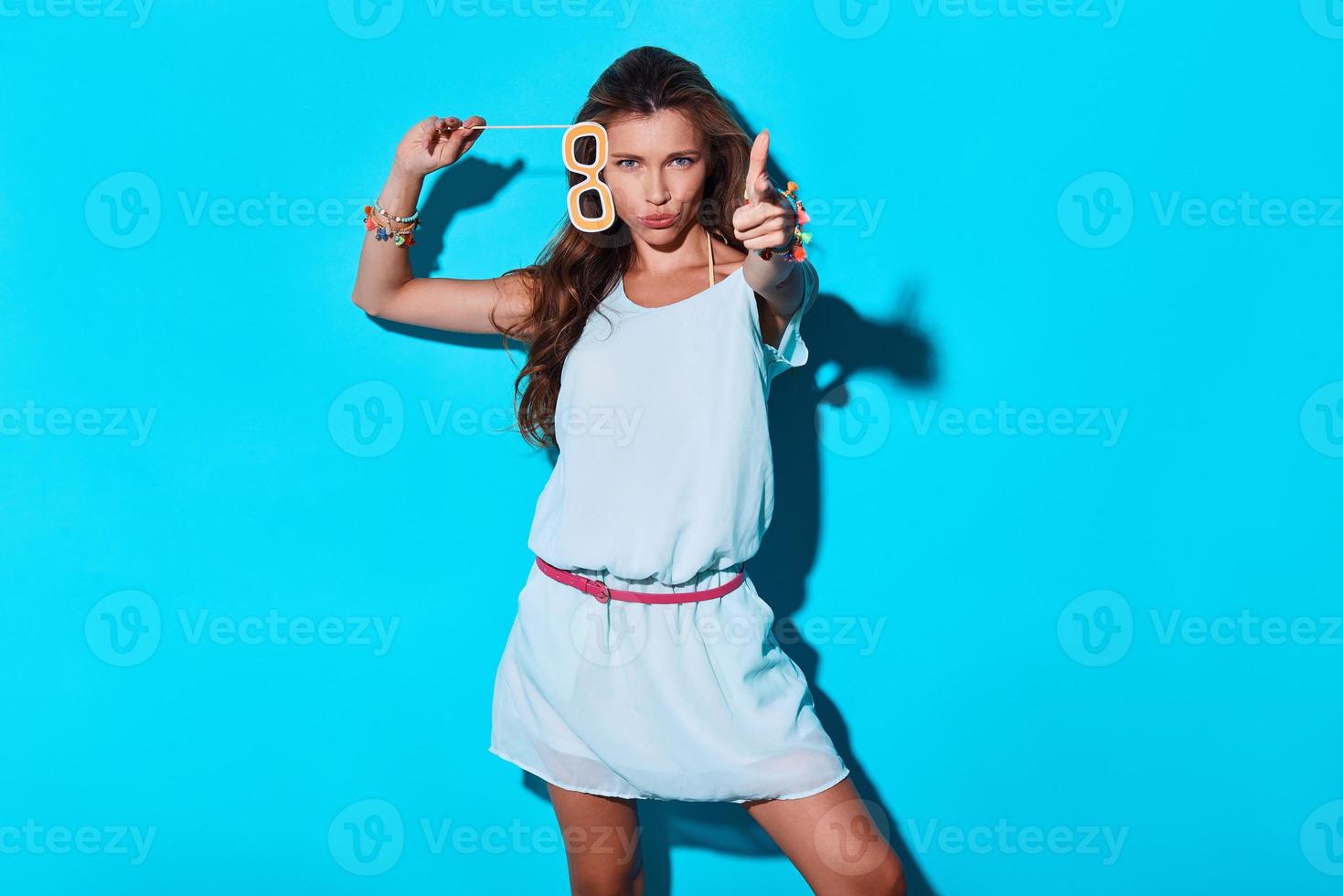 knal aantrekkelijk jong vrouw op zoek Bij camera en gebaren terwijl staand tegen blauw achtergrond foto
