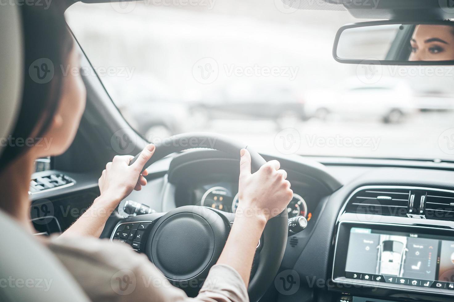 scherpstellen Aan het rijden. achterzijde visie van aantrekkelijk jong vrouw in gewoontjes slijtage op zoek Aan de weg terwijl het rijden een auto foto